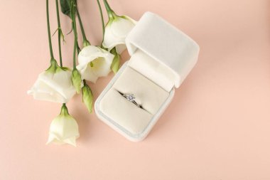 Güzel yüzükler kutuda değerli taşlar ve pembe arka planda çiçekler, düz yatıyordu.