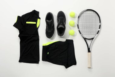 Tenis raketi, toplar ve beyaz arka planda spor giyimi, düz yatış