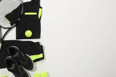 Tenis raketi, toplar ve beyaz arka planda spor giyim, düz yatış. Metin için boşluk