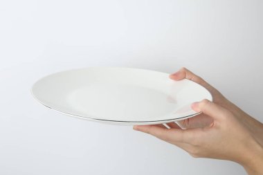 Beyaz arka planda boş seramik plakalı kadın, yakın plan.