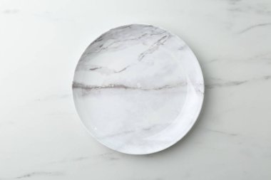 Beyaz mermer masada şık bir tabak, üst görünüm.