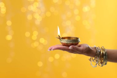 Diwali kutlaması. Sarı arka planda yanan, bulanık ışıkları olan bir kadın, yakın plan. Metin için boşluk