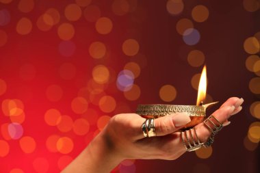 Diwali kutlaması. Kırmızı arka planda yanan, bulanık ışıkları olan bir kadın, yakın plan. Metin için boşluk