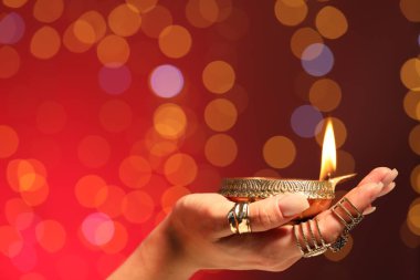 Diwali kutlaması. Kırmızı arka planda yanan, bulanık ışıkları olan bir kadın, yakın plan. Metin için boşluk