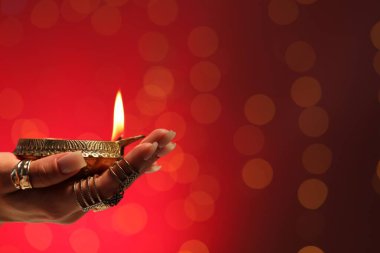 Diwali kutlaması. Kırmızı arka planda yanan, bulanık ışıkları olan bir kadın, yakın plan. Metin için boşluk