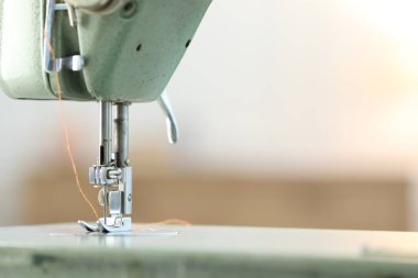 Bulanık arkaplanda ipliği olan dikiş makinesi, makro görünüm. Metin için boşluk