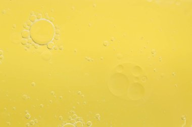Sarı arka planda gerekli yağ kabarcıkları, makro görünüm. Kozmetik ürünü