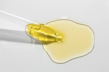 Açık gri arka planda kozmetik yağı ve pipet, yakın plan.