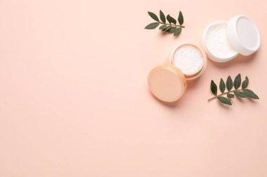 Bej arka planda farklı kozmetik ürünleri ve yapraklar. Metin için boşluk