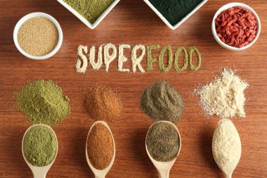 Superfood kelimesi ve ahşap masa üzerindeki farklı sağlıklı tozlar.