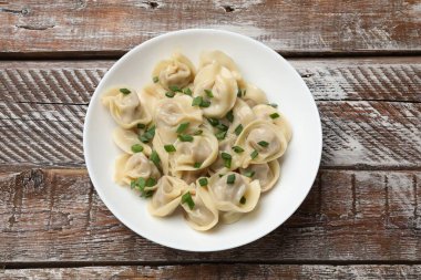 Tahta masadaki yeşil soğanlı leziz pelmeni.