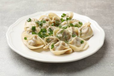 Lezzetli pelmeni yeşil soğanlı ve dereotlu gri desenli masa, yakın plan.