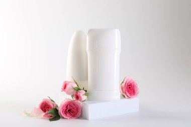Farklı deodorantlar ve beyaz arka planda güzel güller.