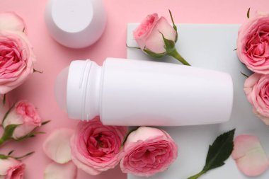 Yuvarlak deodorant ve pembe arka planda güzel gül çiçekleri.