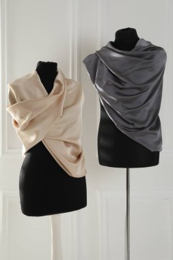 Işık duvarının yanında kumaşa sarılı kadın mankenler.