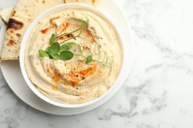 Kırmızı biberli nefis humus ve beyaz mermer masa üzerinde pide, üst manzara.