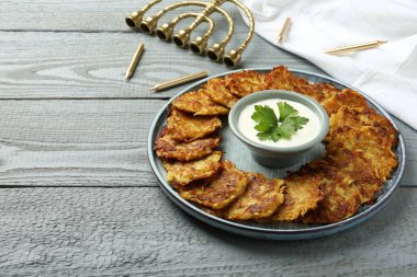 Lezzetli patates krepleri, menorah ve gri ahşap masada mumlar, yakın plan. Hanuka bayramı yemekleri.