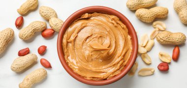 Fıstık ezmesi kasede, yer fıstığı beyaz masada, düz yerde.