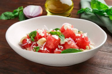 Karpuzlu lezzetli salata, ahşap masada beyaz peynir ve fesleğen.