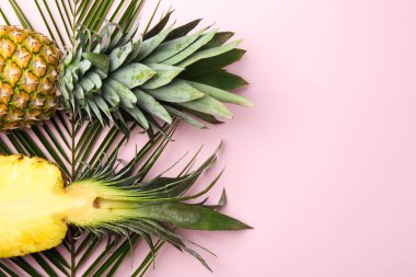 Pembe arka planda taze ananas ve palmiye yaprakları. Metin için boşluk