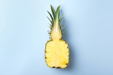 Açık mavi arka planda taze ananasın yarısı, üst manzara