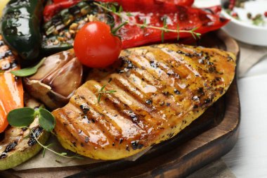 Lezzetli ızgara sebzeler ve tavuk göğsü beyaz masada, yakın plan.