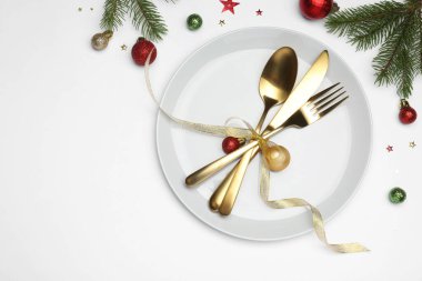 Beyaz arka planda tabak, çatal bıçak takımı ve şenlik dekoruyla Noel sofrası. Metin için boşluk