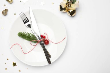 Beyaz arka planda tabak, çatal bıçak takımı ve şenlik dekoruyla Noel sofrası. Metin için boşluk