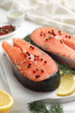 Biberli taze somon bifteği, beyaz masada limon ve dereotu, yakın plan.