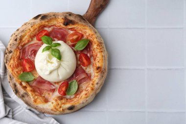 Delicious pizza with burrata cheese, basil, tomato and ham on white tiled table, top view. Space for text clipart