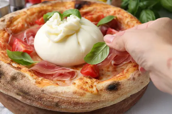 Burrata pizzasına fesleğen ekleyen kadın, yakın plan.