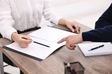 Ofisteki ahşap masada müşteriyle çalışan bankacı, yakın plan.