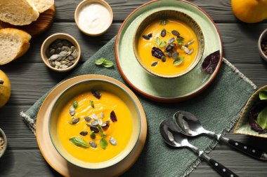 Gri ahşap masada servis edilen lezzetli balkabağı çorbası.