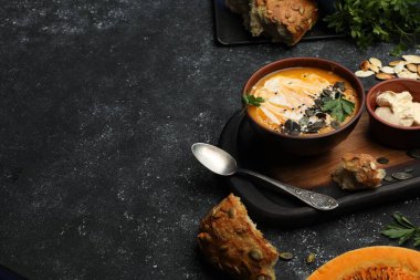 Koyu gri desenli masada servis edilen lezzetli balkabağı çorbası, yakın plan. Metin için boşluk