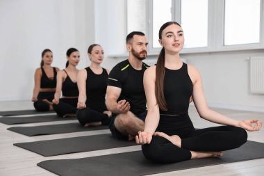 Yoga dersinde minderler üzerinde meditasyon yapan bir grup insan.