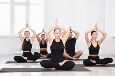 Yoga dersinde minderler üzerinde meditasyon yapan bir grup insan.