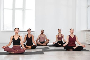 Yoga dersinde minderler üzerinde meditasyon yapan bir grup insan.