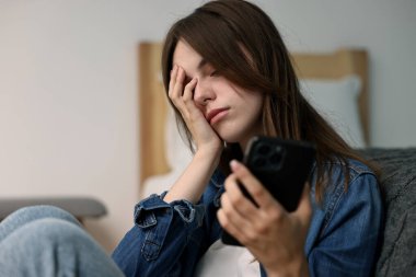 Yalnızlık kavramı. Evde akıllı telefonu olan üzgün genç kız.