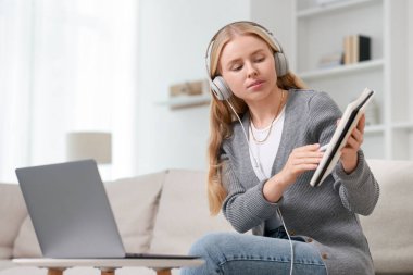 Kulaklıklarda tercüman evdeki kanepede dizüstü bilgisayarla görüntülü konuşma yapıyor.