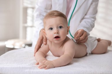 Pediyatrist, klinikte steteskoplu küçük bir çocuğu muayene ediyor. Bebeğin sağlığını kontrol ediyorum.