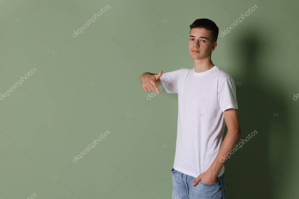 Teenage boy wearing white t-shirt on green background, space for text