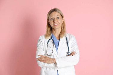 Pembe arka planda steteskobu olan doktor portresi.