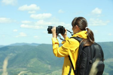 Sırt çantalı ve kameralı fotoğrafçı güzel dağların fotoğrafını çekiyor.