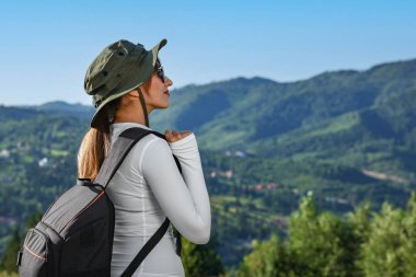 Güneş gözlüklü, güzel dağlarda sırt çantalı genç bir kadın.