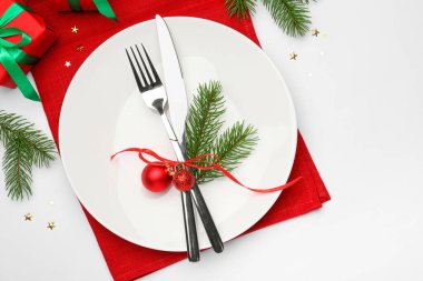 Beyaz arka planda tabak, çatal bıçak, peçete ve şenlikli Noel sofrası.