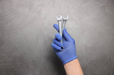 Gri desenli arka planda anahtarı olan oto tamircisi, yakın plan