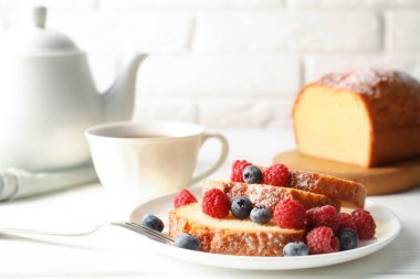 Taze pişmiş sünger keki, ahududu ve yaban mersini beyaz ahşap masada.
