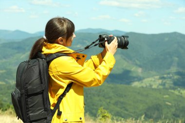 Sırt çantalı ve kameralı fotoğrafçı güzel dağların fotoğrafını çekiyor.