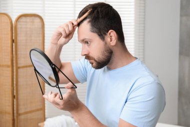 Adam aynanın içinde saçını tarıyor. Alopecia sorunu