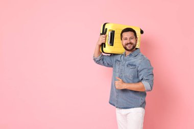 Bavullu mutlu adam pembe arka planda baş parmak gösteriyor, mesaj için boşluk var.